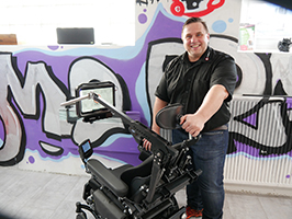 Photo du directeur général Thomas Rosner avec le MyEcc installé sur un fauteuil roulant.